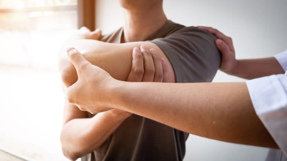 Personal trainer helping client stretch shoulder